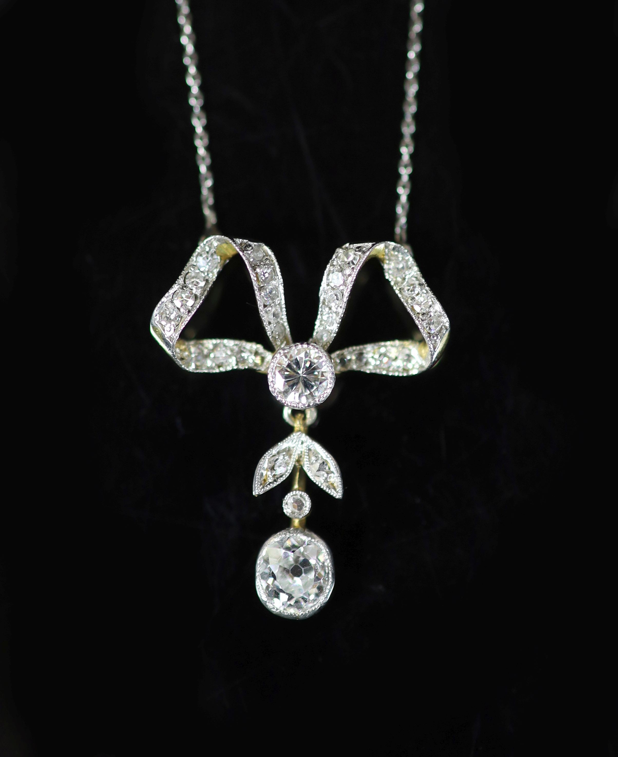 An early 20th century gold, platinum and diamond set drop ribbon bow pendant necklace